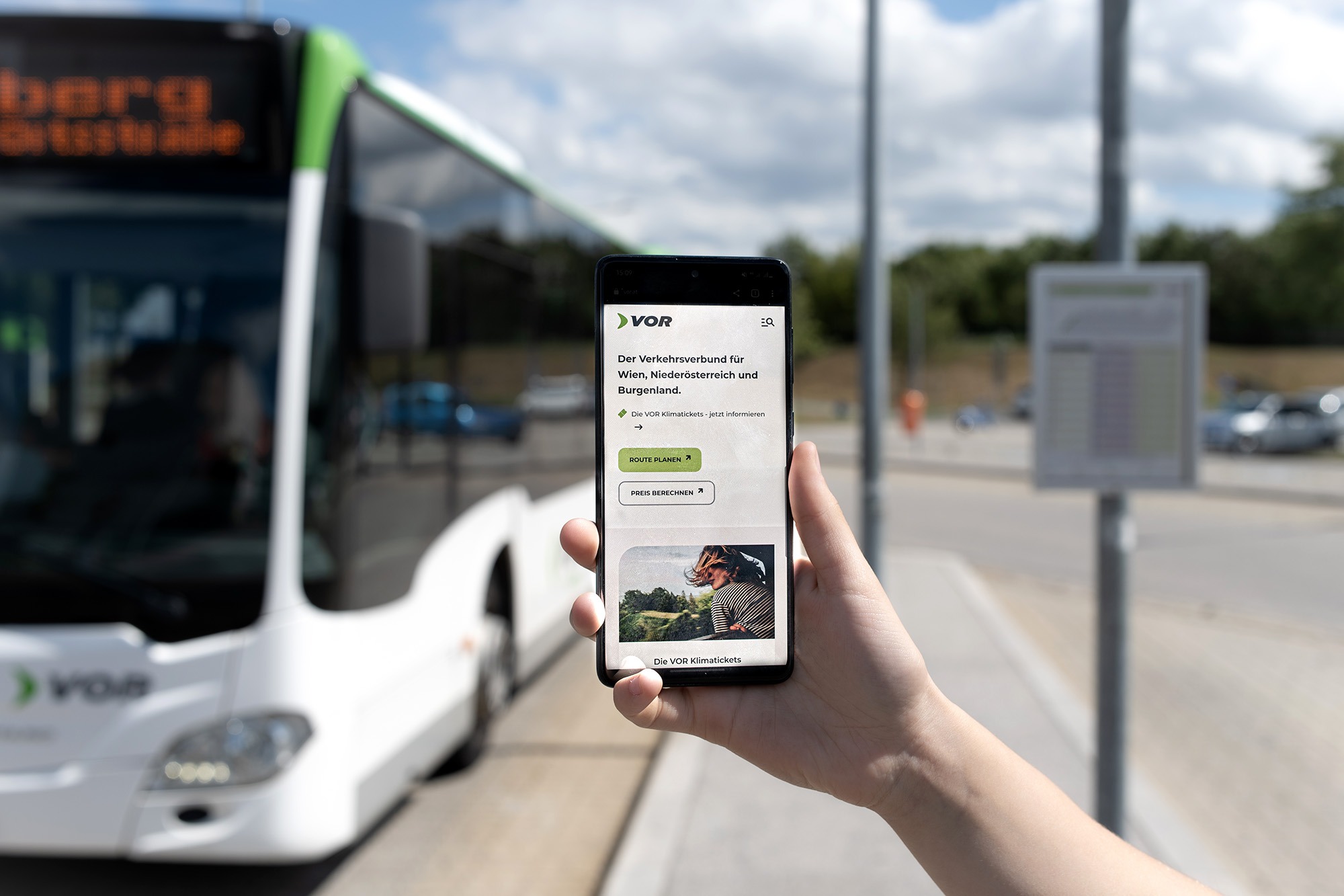 Der Viewport der mobilen VOR-Website auf einem Smartphone vor einem gebrandeten VOR-Bus.