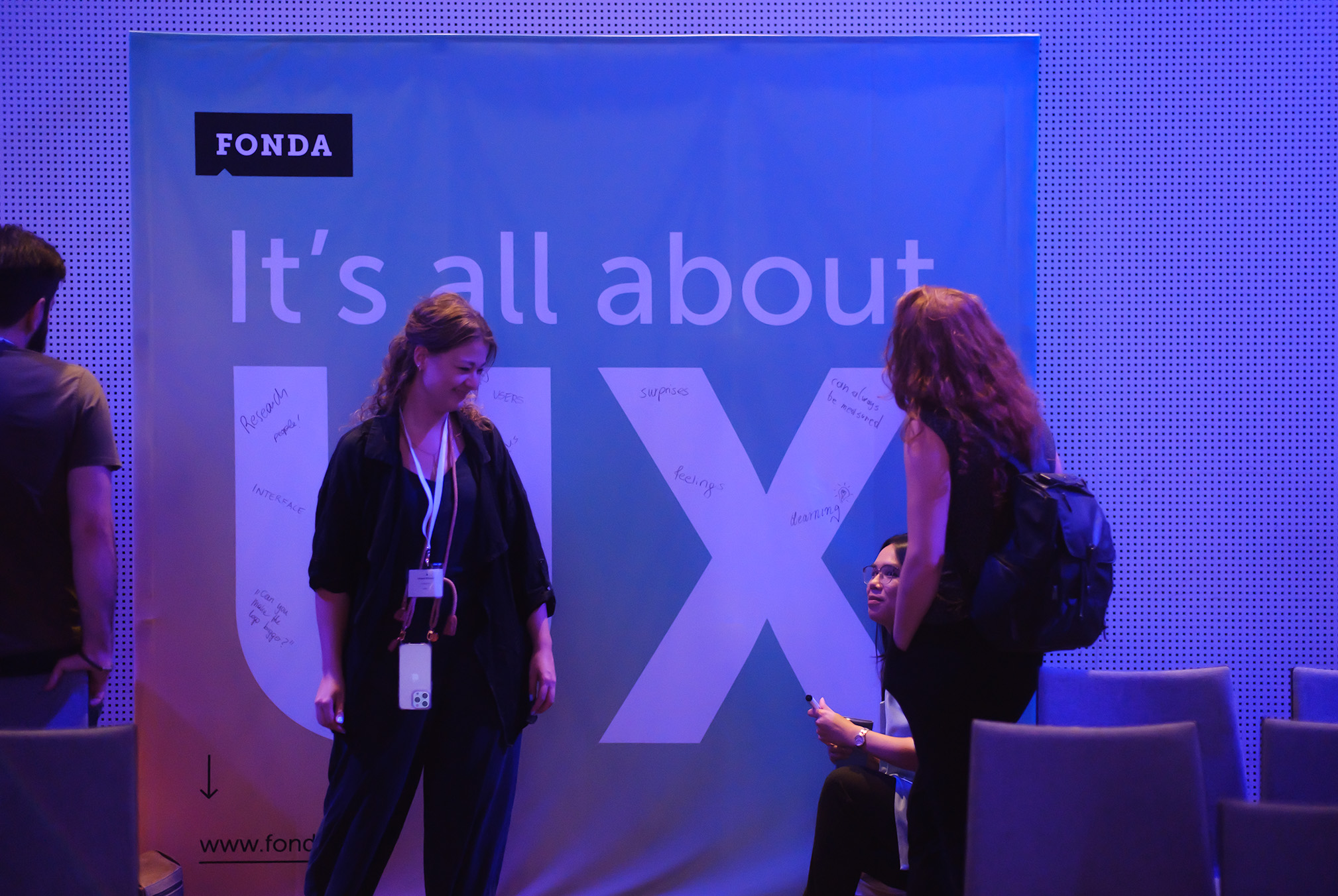 Eine Besucherin der UXCon 2022 steht vor der FONDA Fotowall, auf der der Slogan 