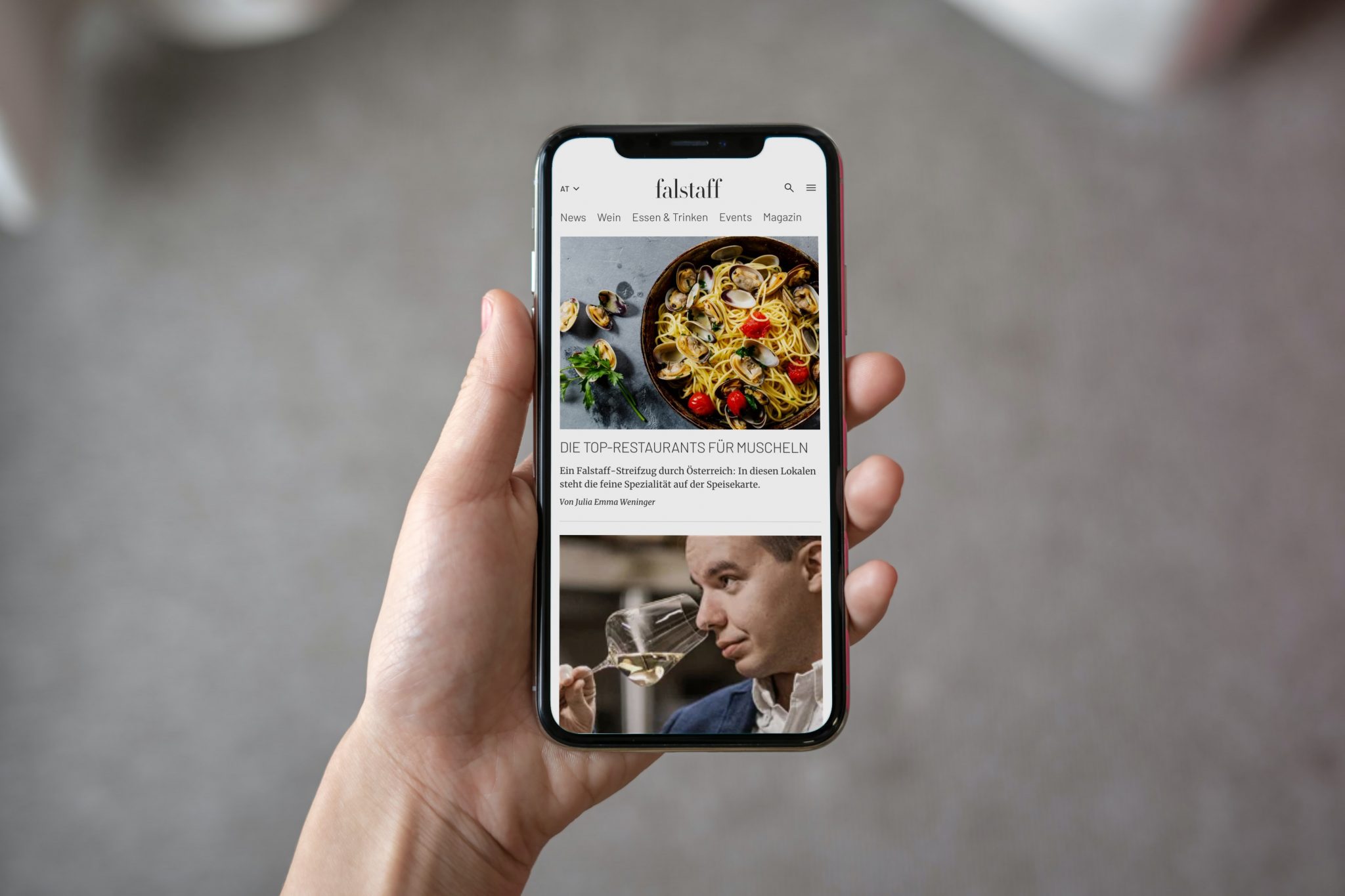 Eine Hand hält ein iPhone, auf dem die Falstaff Website abgebildet ist